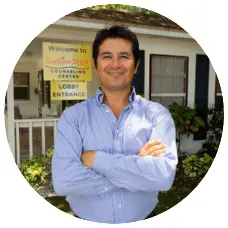Andrés Ariza, Office Manager at Sunshine State Counseling Center, standing confidently outside the center's lobby entrance, welcoming clients.