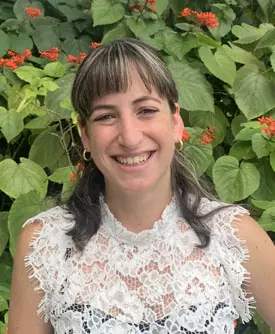 Elizabeth Martin, consejera en Sunshine State Counseling Center, sonriendo frente a un fondo de plantas verdes y flores, representando servicios de terapia en Bonita Springs.