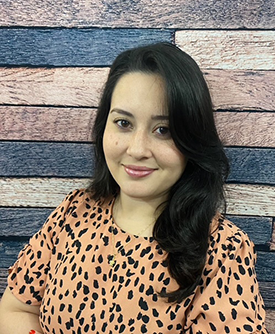 Thalia Suarez, consejera en Sunshine State Counseling Center, con fondo de madera en tonos azules y rosas, ofreciendo servicios de terapia en español en Bonita Springs, FL.